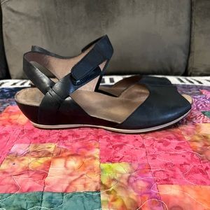 Dansko black leather wedge sandals with Velcro closure on ankle strap.